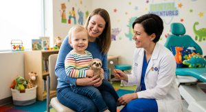 Toddler on parent's lap during first dental visit with friendly dentist in London, Ontario